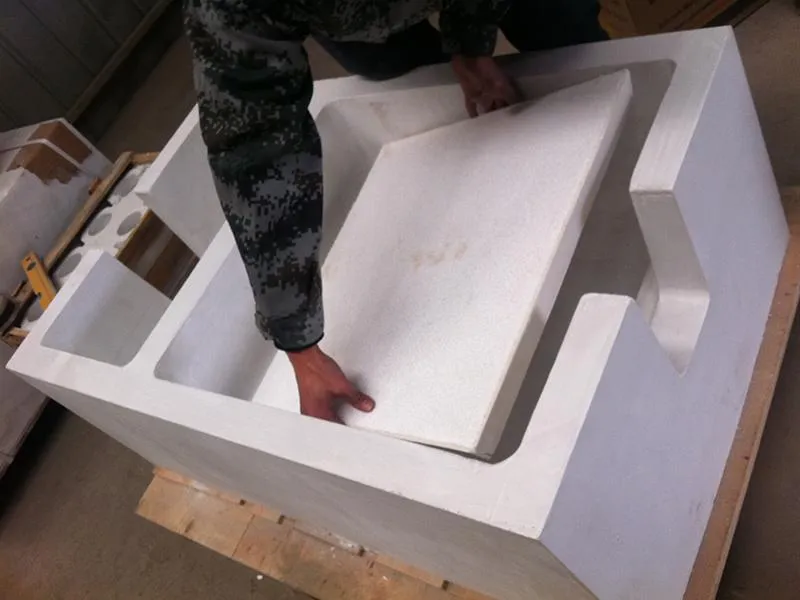 Worker installing a ceramic foam filter into a filtration box in a foundry, carefully positioning the filter for molten metal filtration during the casting process.